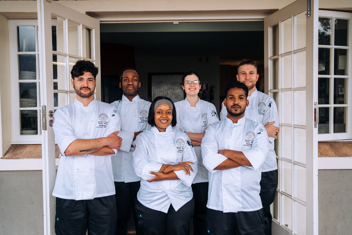 Group of chefs posing together in front of a building entrance.