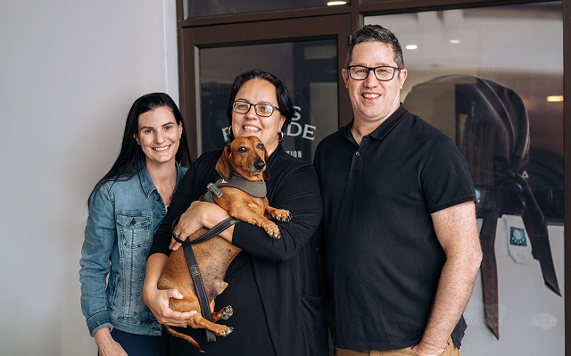 Three adults and a dog standing together